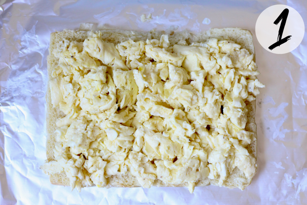 Savory Hawaiian rolls sliced horizontally with the bottom layer topped with scrambled eggs
