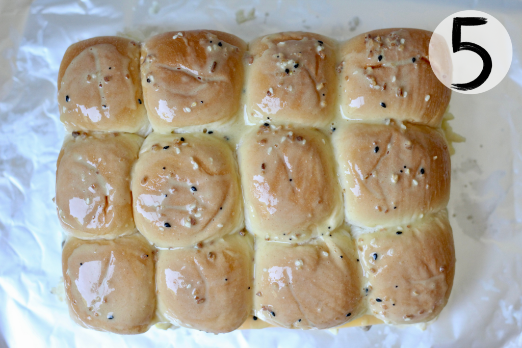 Melted butter and Dijon mixture being brushed over assembled breakfast sliders