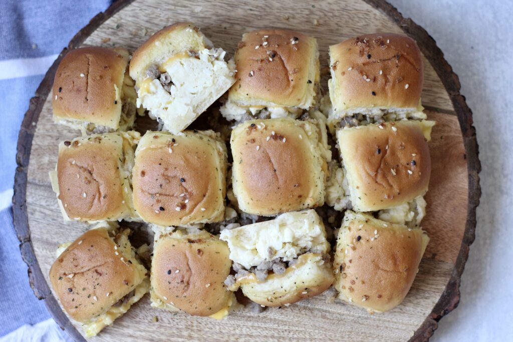 Baked breakfast sliders on wooden platter cut and spread out
