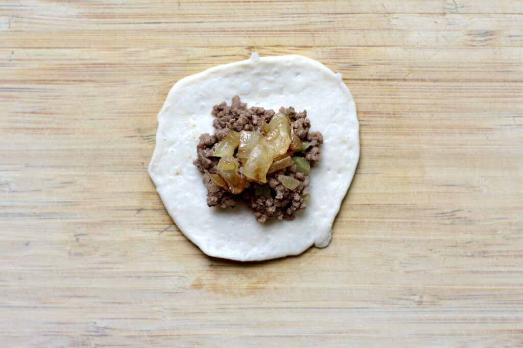 Ground beef filling placed in the center of refrigerated biscuit dough