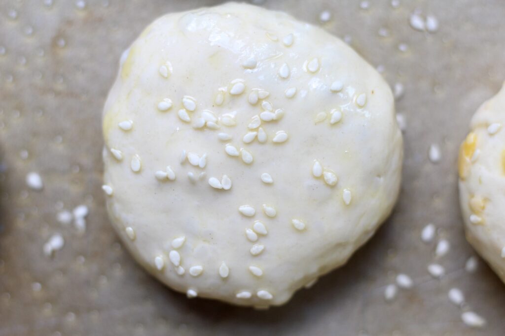 Unbaked cheeseburger bombs topped with egg wash and sesame seeds