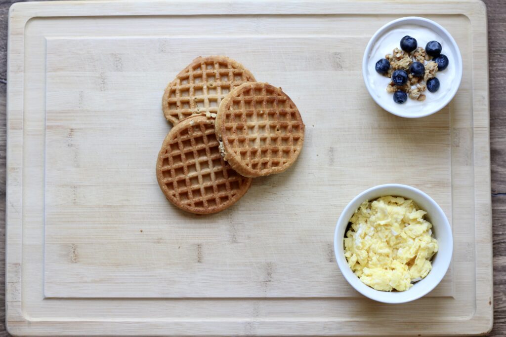 Protein waffles, scrambled eggs, and yogurt arranged as the first step in building a breakfast board